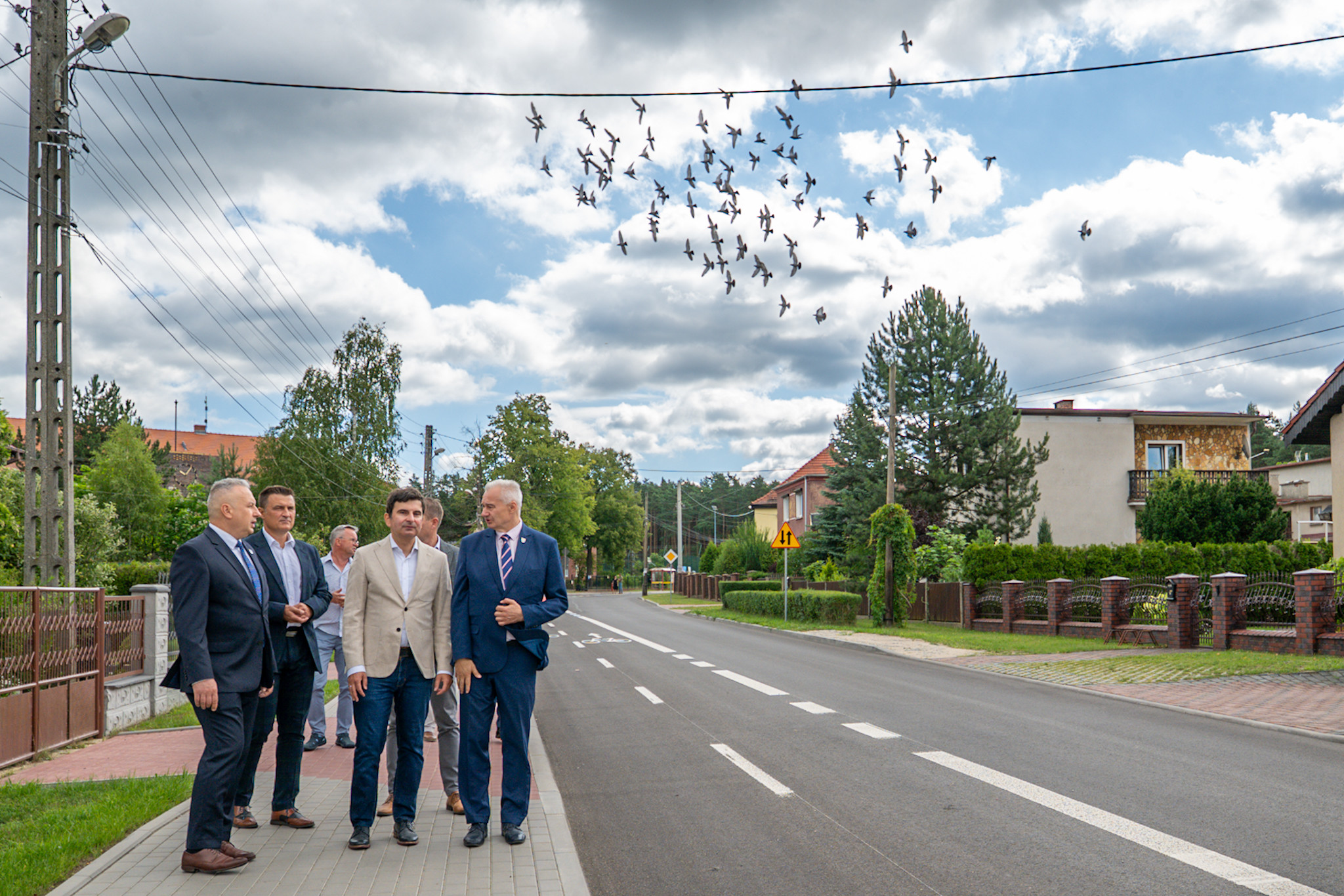 Wojewoda Śląski i samorządowcy idą chodnikiem nowej drogi.