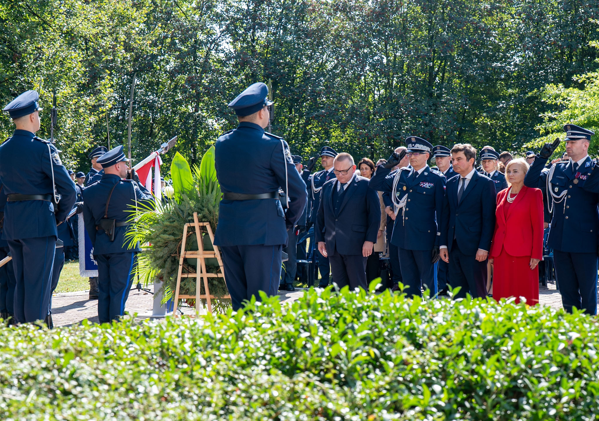 Uczestnicy wydarzenia składają kwiaty pod pomnikiem.