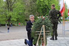 Wojewoda Jarosław Wieczorek poprawia szarfę na wieńcu/foto: ŚUW