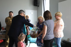 Wizyta Wojewody Śląskiego w siedzibie OSP Rybnik-Kamień - Wojewoda wręcza upominek uchodźcom /fot. A. Księżnik/
