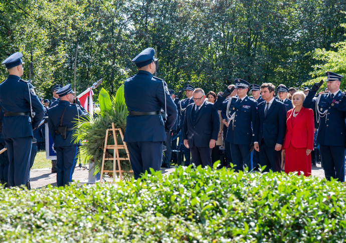 Uczestnicy wydarzenia składają kwiaty pod pomnikiem.
